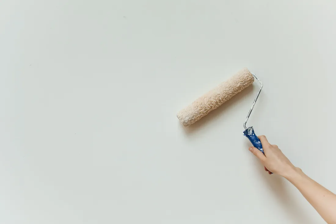Rouleau de peinture appliqué sur un mur intérieur blanc
